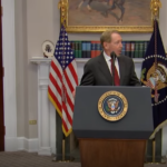 El Presidente de EE. UU. Donald Trump a la izquierda, Larry Ellison (CEO de Oracle) en el podio central, y Masayoshi Son (CEO de SoftBank) a la derecha, en la Casa Blanca con banderas estadounidenses de fondo.